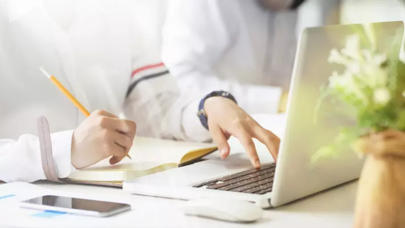 Woman blogging on laptop and writing on notebook